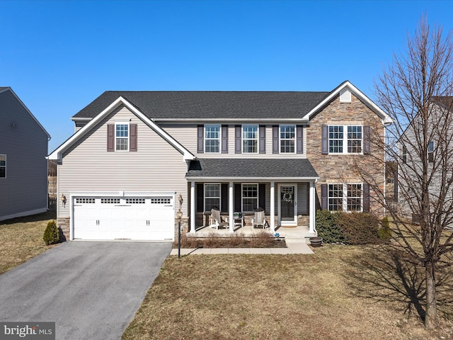 traditional-style home with stone siding, a porch, driveway, an attached garage, and a shingled roof