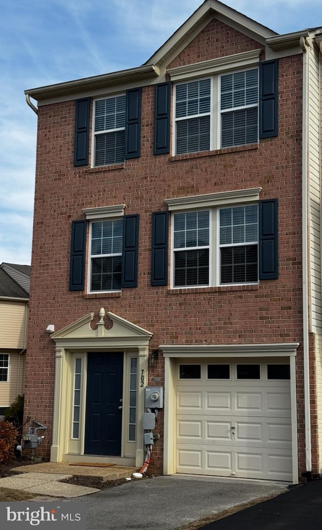 multi unit property featuring a garage, brick siding, and aphalt driveway