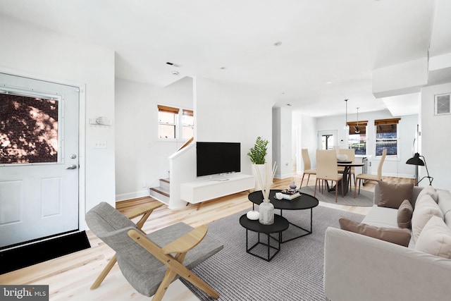 living area with light wood-style floors, stairs, and baseboards