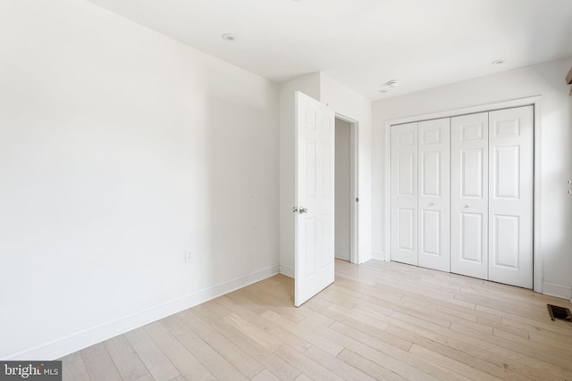 unfurnished bedroom featuring a closet, light wood-style flooring, and baseboards