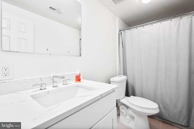 bathroom with toilet, vanity, and visible vents