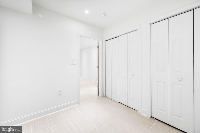 unfurnished bedroom featuring baseboards and two closets