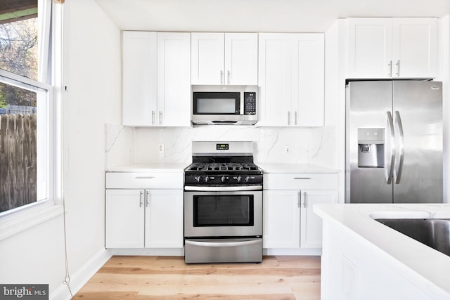 kitchen with appliances with stainless steel finishes, white cabinets, and tasteful backsplash