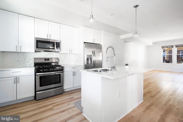 kitchen featuring light countertops, appliances with stainless steel finishes, decorative light fixtures, and white cabinetry