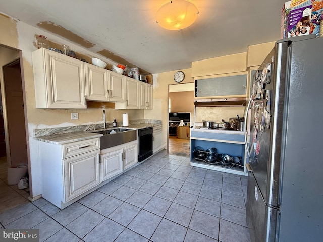 kitchen with light tile patterned floors, freestanding refrigerator, white cabinetry, a sink, and dishwasher