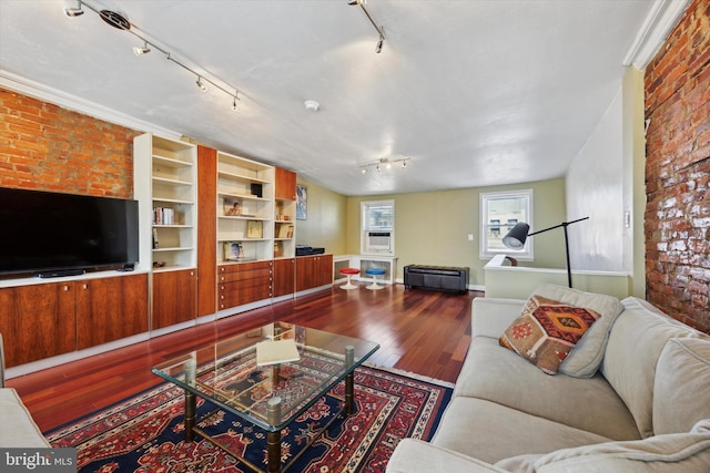 living area with track lighting, brick wall, and wood finished floors