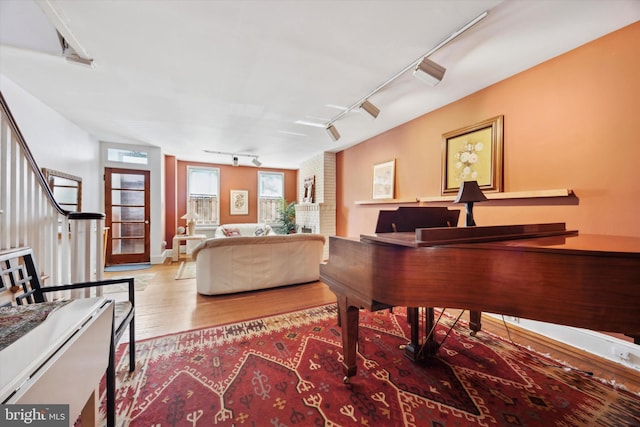 sitting room with stairs, track lighting, and wood finished floors