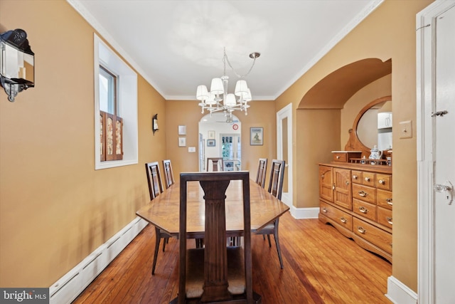 dining area with crown molding, light wood finished floors, a baseboard heating unit, a chandelier, and baseboards