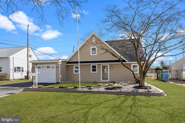 view of front of house featuring a garage, driveway, fence, and a front lawn