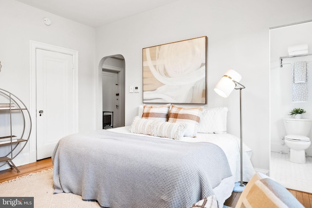 bedroom featuring arched walkways and wood finished floors