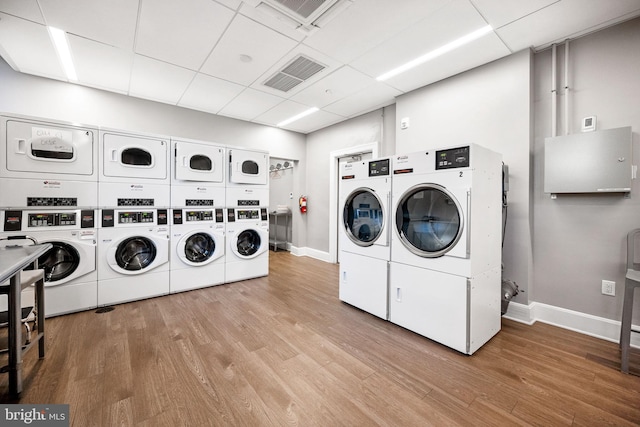 shared laundry area featuring separate washer and dryer, wood finished floors, visible vents, baseboards, and stacked washer / drying machine