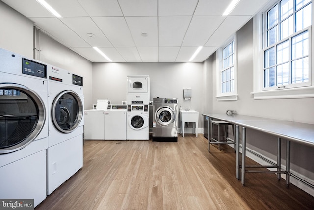 shared laundry area featuring light wood finished floors, separate washer and dryer, and stacked washer / drying machine