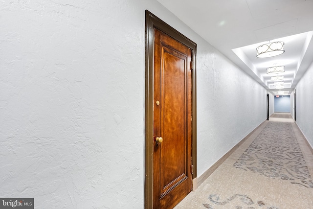 hallway with a textured wall and baseboards