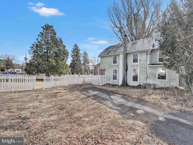 back of house featuring a chimney and fence