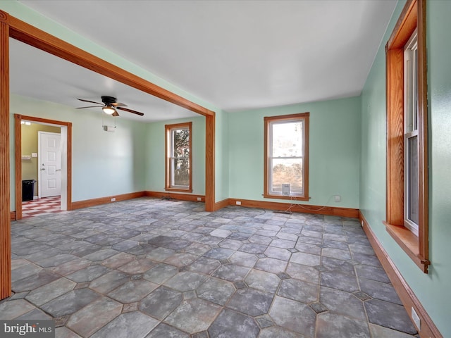 empty room with a ceiling fan and baseboards