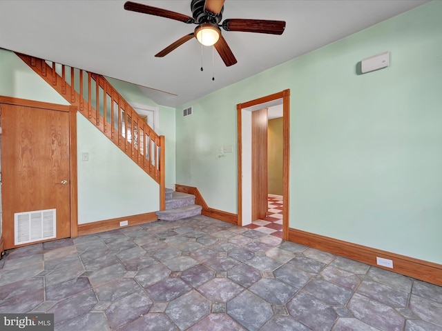 empty room featuring baseboards, stairs, visible vents, and ceiling fan