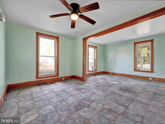 spare room featuring a ceiling fan and baseboards