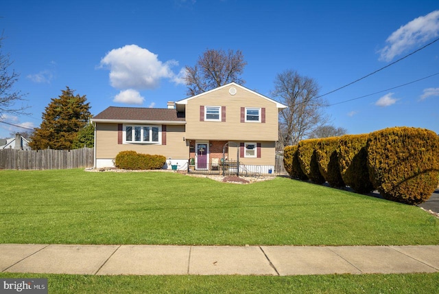 tri-level home with fence and a front lawn