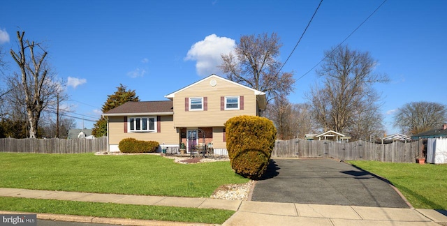 tri-level home featuring fence and a front lawn