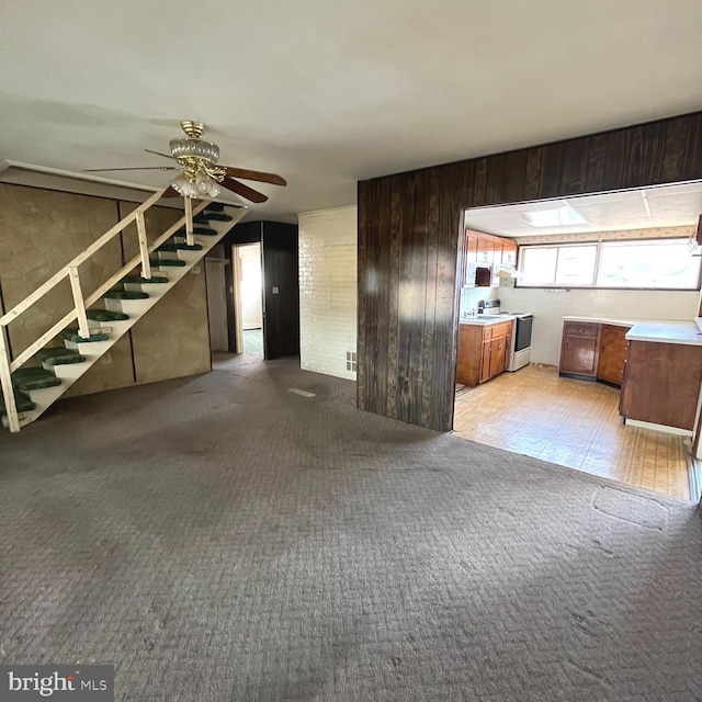 basement featuring light carpet, ceiling fan, and stairs