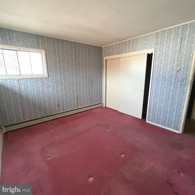 unfurnished bedroom featuring carpet, a closet, baseboard heating, and wallpapered walls