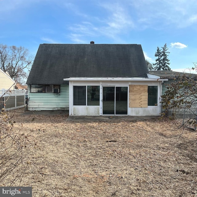 back of property with fence and a sunroom