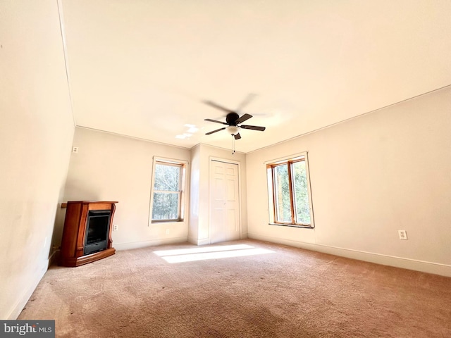 unfurnished living room featuring a wealth of natural light, carpet, and baseboards