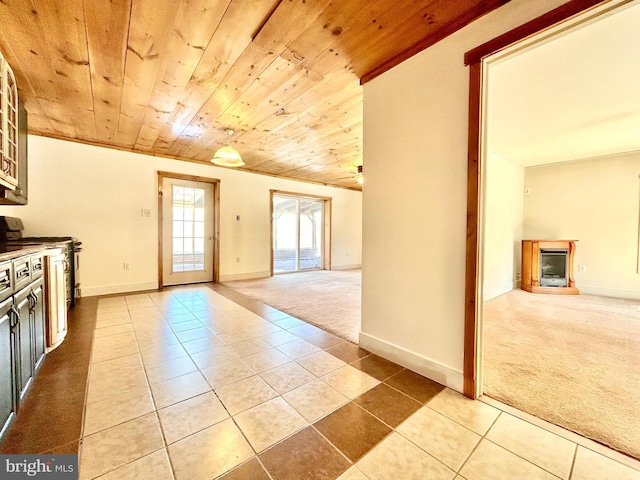 interior space with a fireplace, wood ceiling, carpet flooring, baseboards, and tile patterned floors