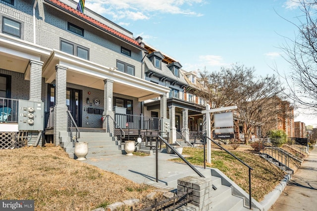 view of front facade featuring a porch, brick siding, and mansard roof