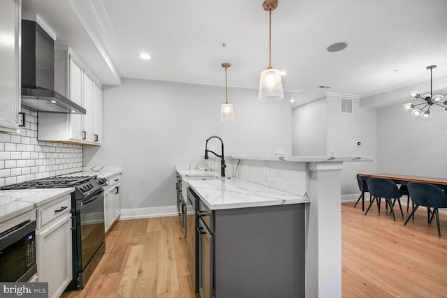 kitchen featuring a sink, visible vents, wall chimney exhaust hood, decorative backsplash, and black appliances