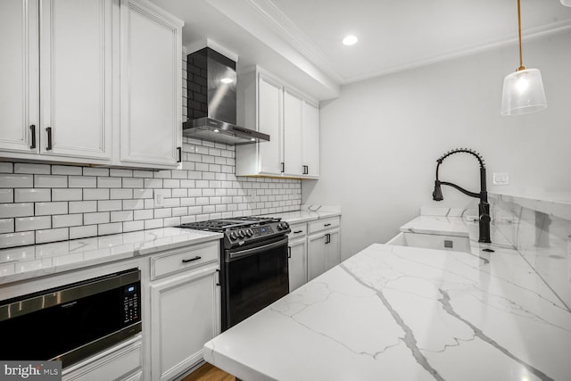 kitchen featuring stainless steel appliances, decorative backsplash, white cabinets, a sink, and wall chimney range hood