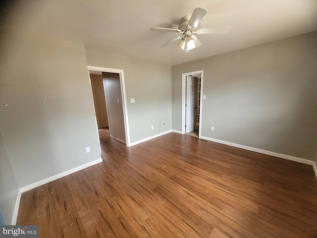 empty room with ceiling fan, wood finished floors, and baseboards