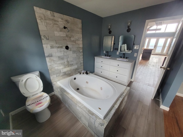 full bathroom featuring double vanity, a sink, a whirlpool tub, and wood finished floors