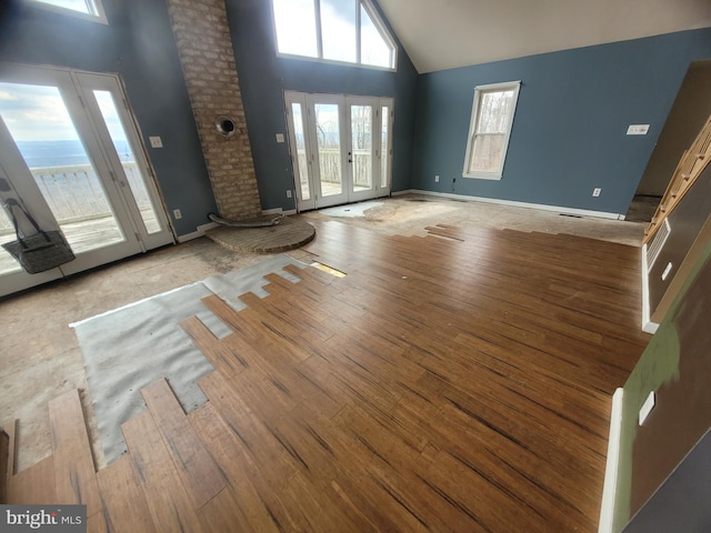 entrance foyer with high vaulted ceiling, french doors, wood-type flooring, and baseboards