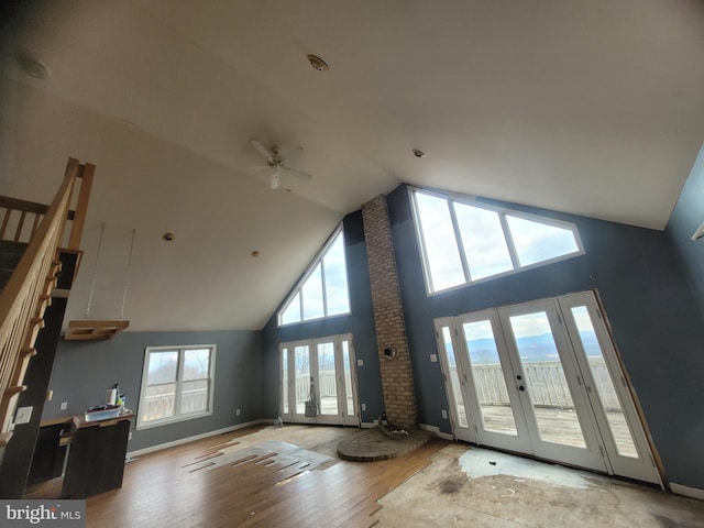 unfurnished living room featuring baseboards, stairway, wood finished floors, french doors, and high vaulted ceiling