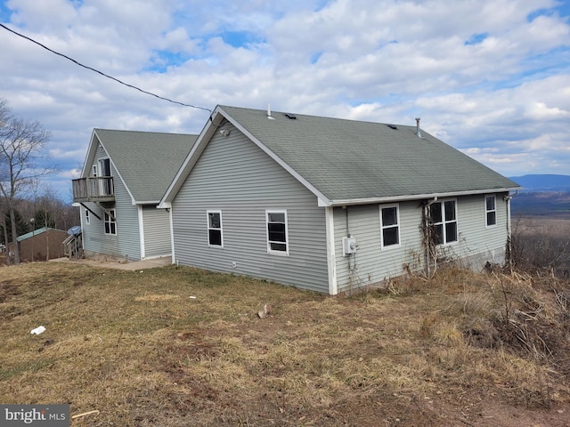 back of property featuring a shingled roof and a lawn