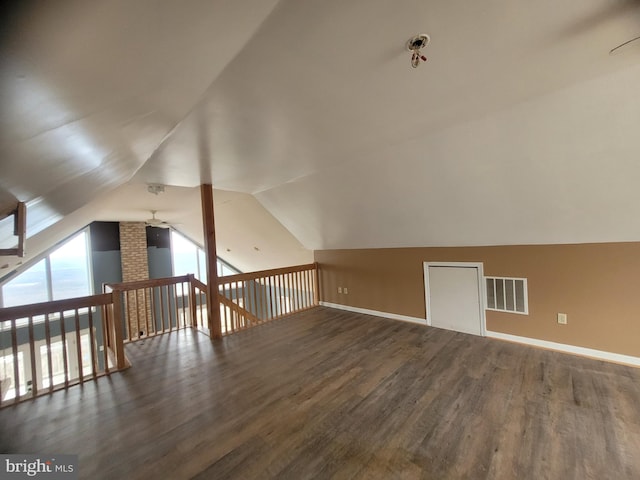 additional living space featuring baseboards, visible vents, vaulted ceiling, and wood finished floors