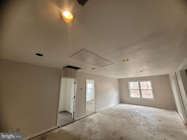 interior space featuring concrete flooring, attic access, and baseboards