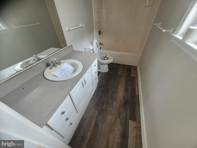 full bathroom with toilet, washtub / shower combination, wood finished floors, and vanity