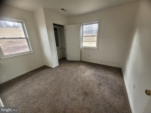 unfurnished bedroom featuring carpet flooring, visible vents, and baseboards