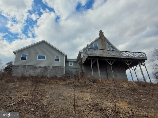 back of property with a chimney and a wooden deck