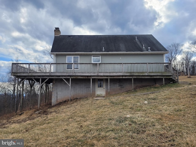 back of property with a wooden deck, a chimney, and a yard