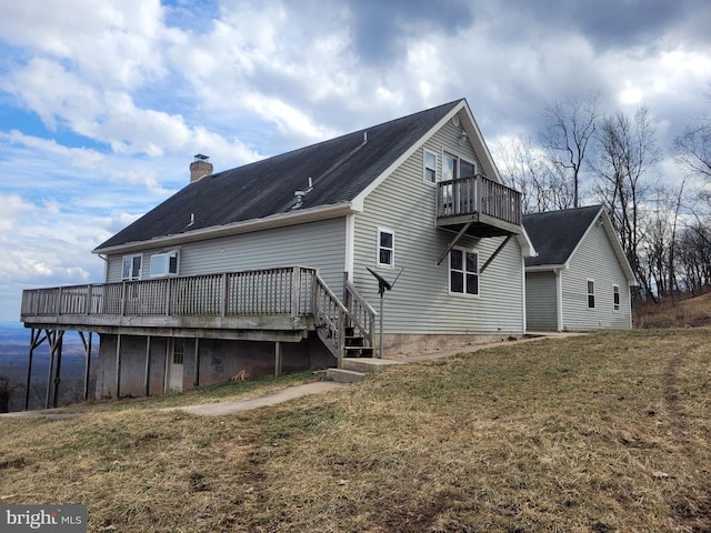 back of house featuring a balcony, a chimney, and a lawn