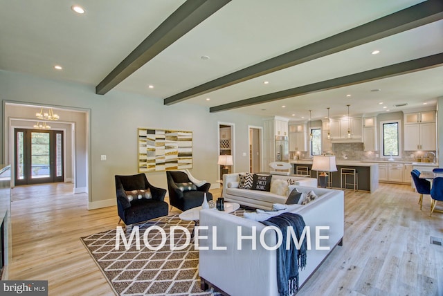 living area with a chandelier, recessed lighting, baseboards, light wood-type flooring, and beam ceiling