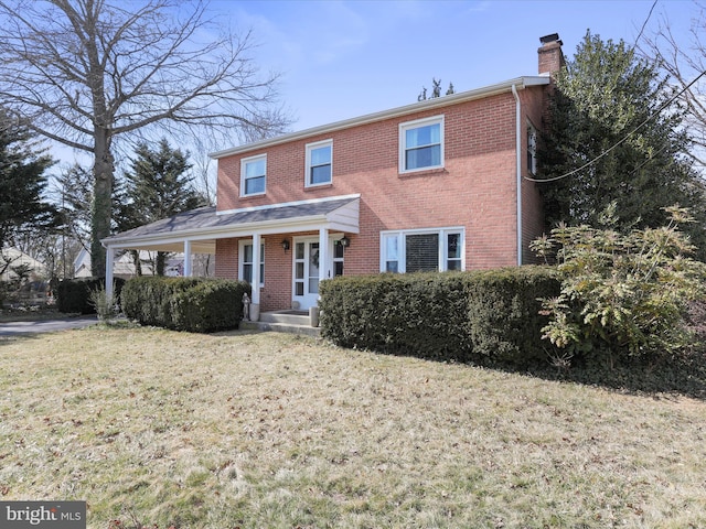 view of front of property with a front yard, a chimney, and brick siding