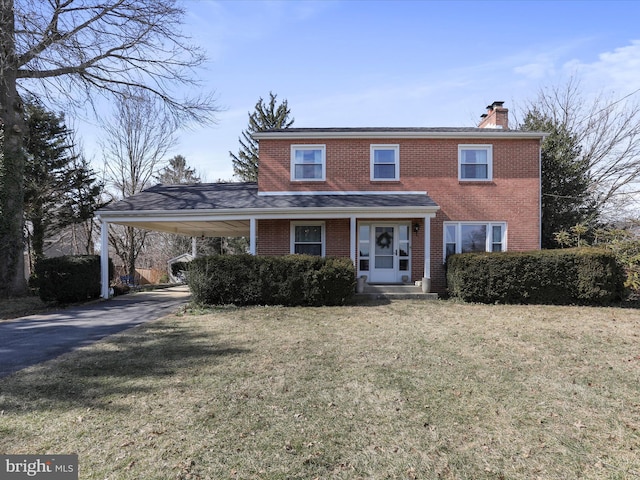 view of front facade featuring brick siding, a chimney, a carport, driveway, and a front lawn