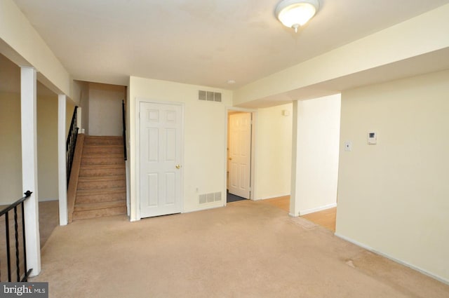 spare room with stairway, visible vents, light carpet, and baseboards