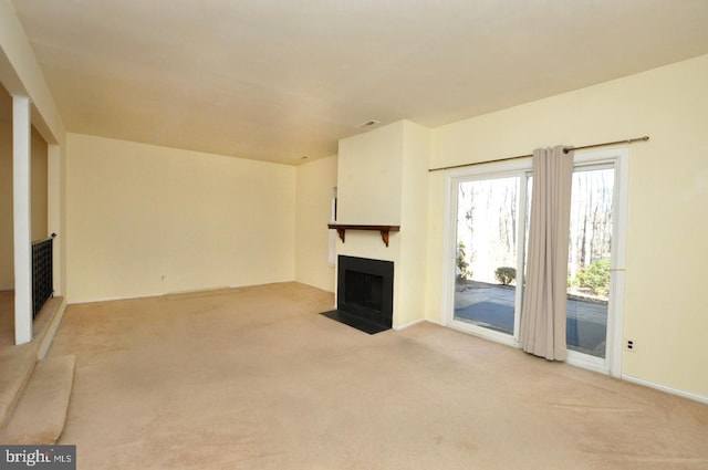 unfurnished living room featuring light carpet and a fireplace with flush hearth