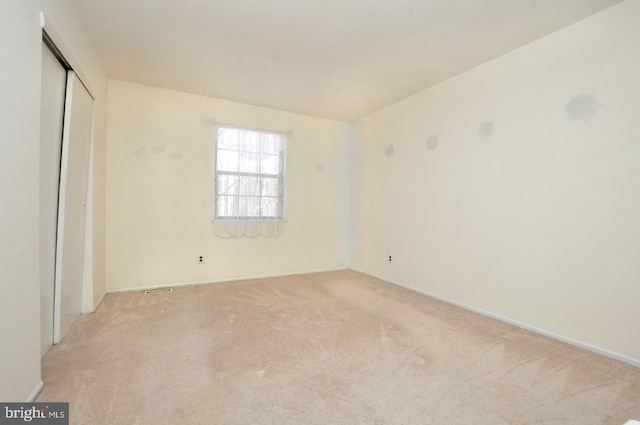 unfurnished bedroom featuring baseboards, a closet, and light colored carpet