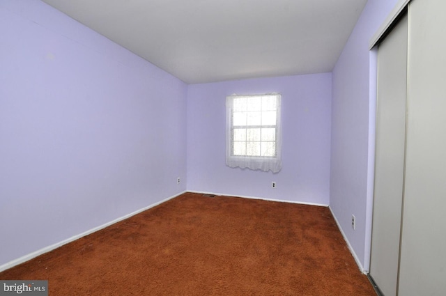 unfurnished room with dark colored carpet and baseboards